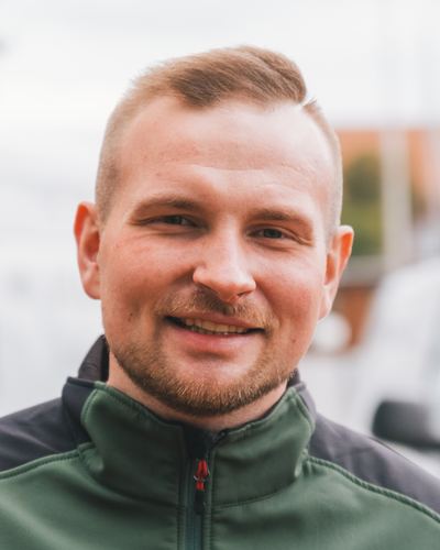 Meik Mroz, Inhaber von MM Dienstleistungen, lächelnd in der grünen Firmenjacke